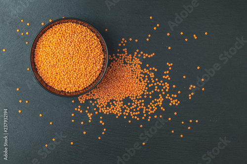 Red lentils in black plate on black stone table background