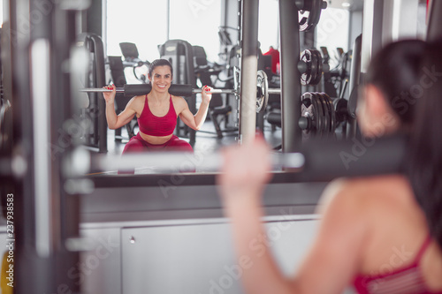 Cheerful woman squatting in gym