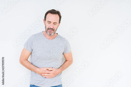 Handsome senior man over isolated background with hand on stomach because indigestion, painful illness feeling unwell. Ache concept.