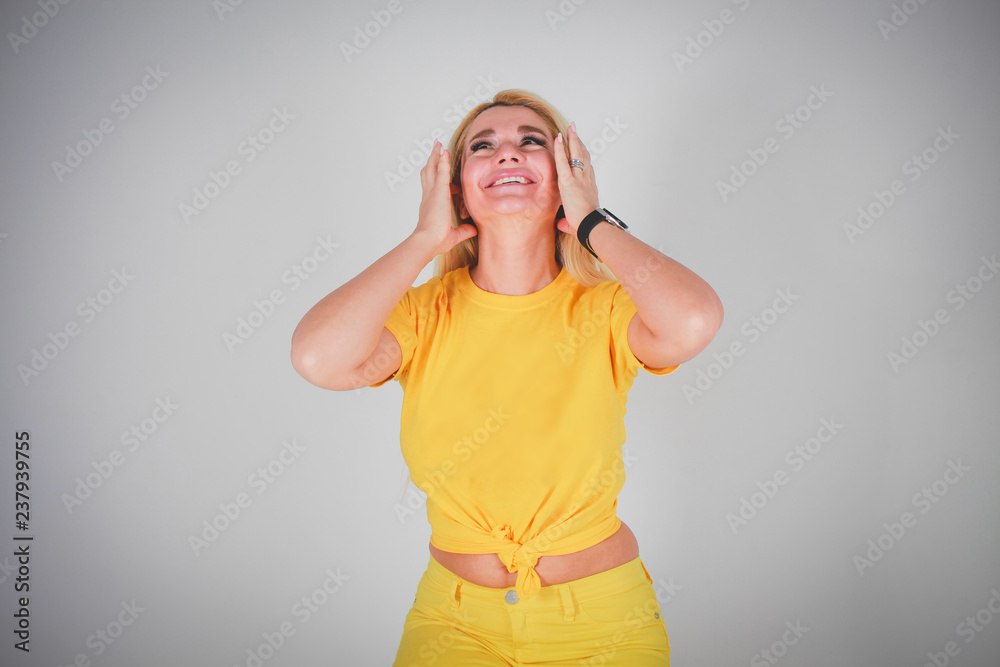 A girl in a yellow shirt with yellow pants, head thrown back, straightens her hair, smiles insanely. A girl in a yellow shirt with yellow pants, head thrown back, straightens her hair, smiles insanely.