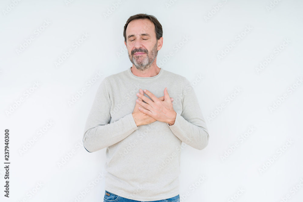 Elegant senior man over isolated background smiling with hands on chest with closed eyes and grateful gesture on face. Health concept. Elegant senior man over isolated background smiling with hands on chest with closed eyes and grateful gesture on face. Health concept.