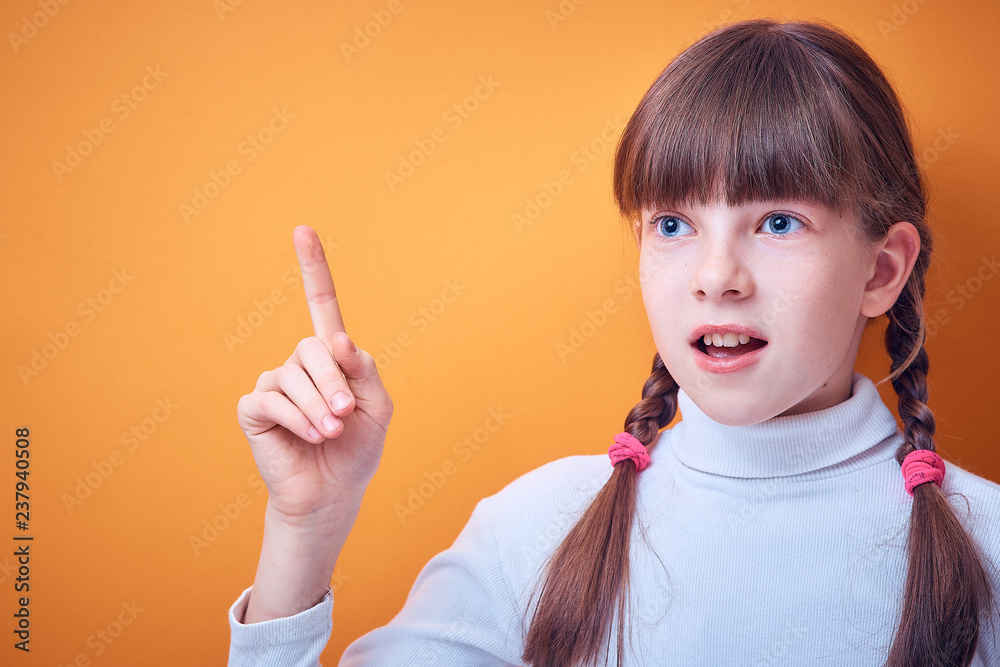 conceptual idea, Caucasian teen girl shows index finger up on colored background, place for text conceptual idea, Caucasian teen girl shows index finger up on colored background, place for text
