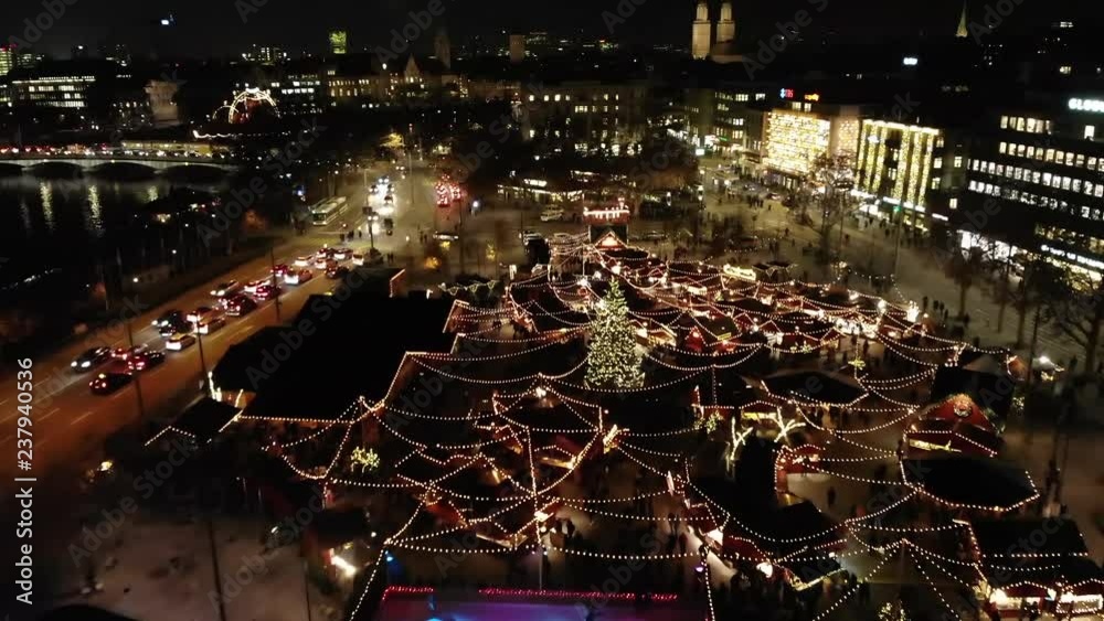 Night Drone shot of Christmas Market flying low in Z√ºrich, Switzerland with illuminated Christmas Tree