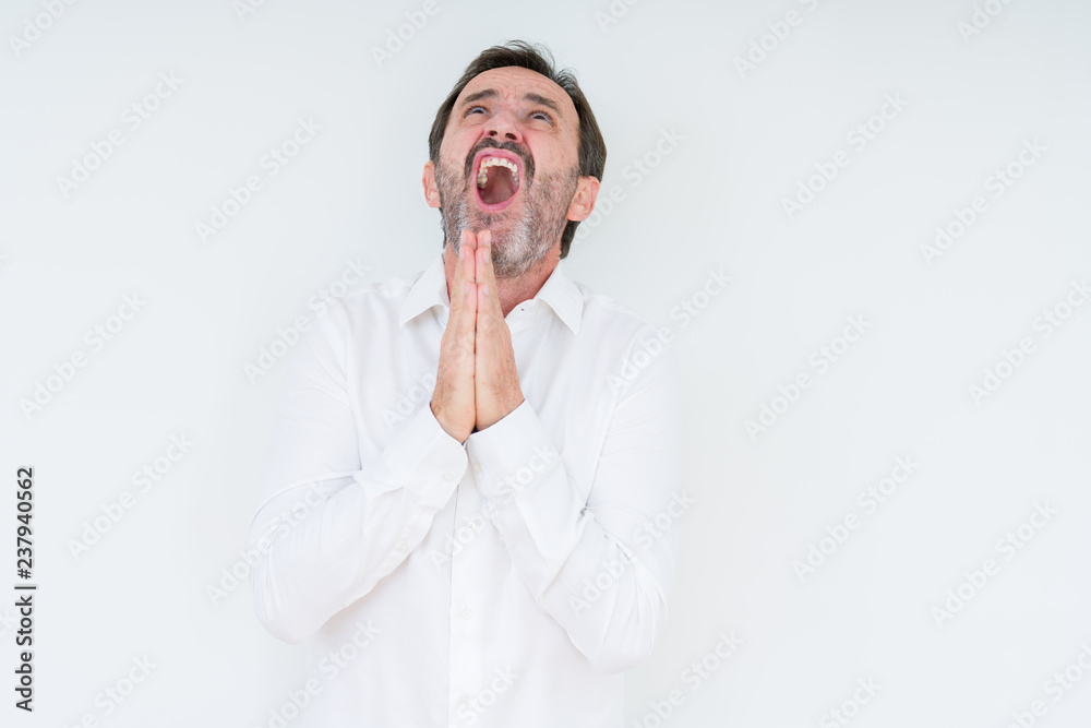 Elegant senior man over isolated background begging and praying with hands together with hope expression on face very emotional and worried. Asking for forgiveness. Religion concept. Elegant senior man over isolated background begging and praying with hands together with hope expression on face very emotional and worried. Asking for forgiveness. Religion concept.