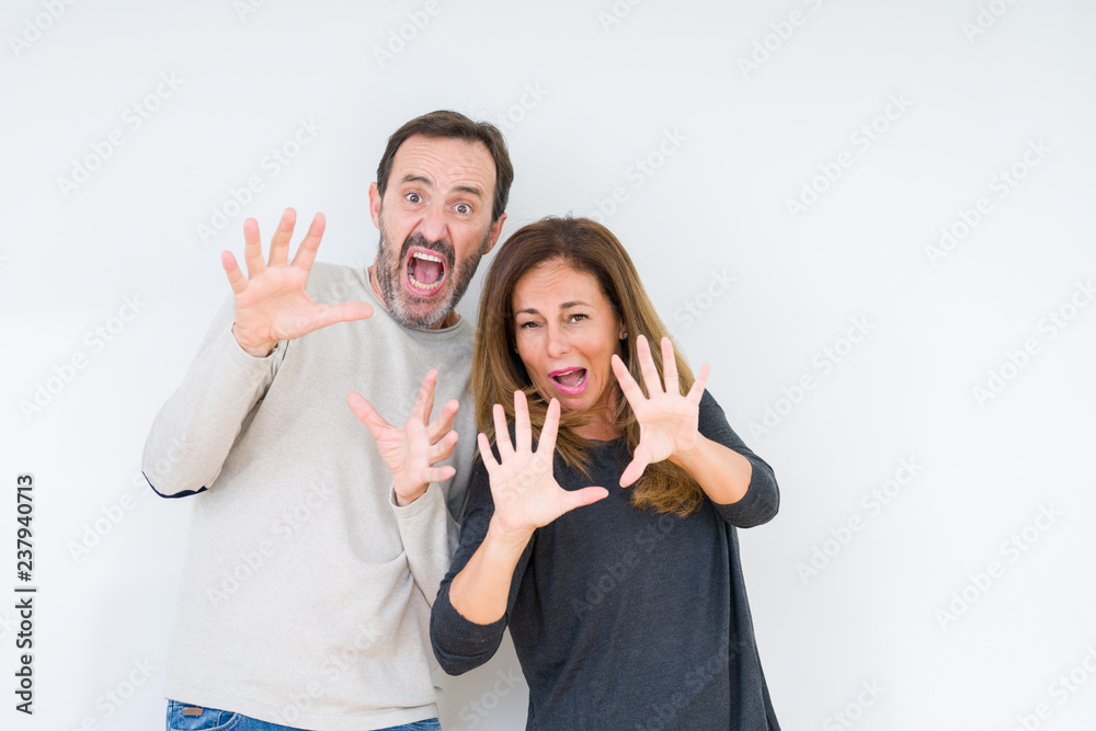 Beautiful middle age couple in love over isolated background afraid and terrified with fear expression stop gesture with hands, shouting in shock. Panic concept. Beautiful middle age couple in love over isolated background afraid and terrified with fear expression stop gesture with hands, shouting in shock. Panic concept.