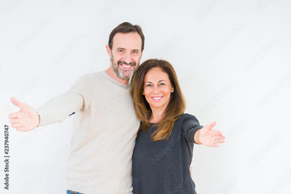 Beautiful middle age couple in love over isolated background looking at the camera smiling with open arms for hug. Cheerful expression embracing happiness. Beautiful middle age couple in love over isolated background looking at the camera smiling with open arms for hug. Cheerful expression embracing happiness.