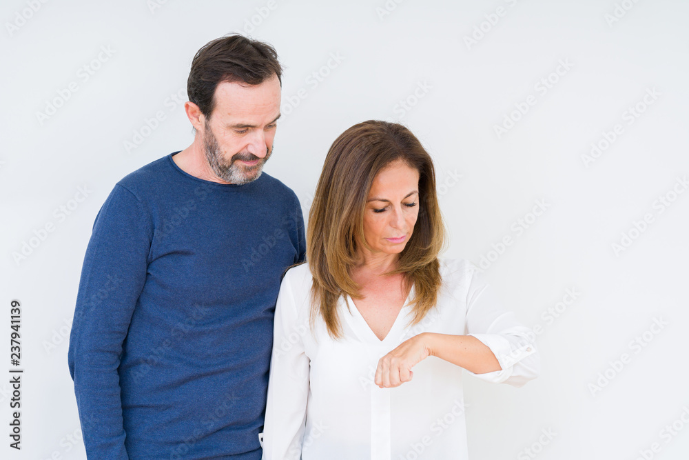 Beautiful middle age couple in love over isolated background Checking the time on wrist watch, relaxed and confident Beautiful middle age couple in love over isolated background Checking the time on wrist watch, relaxed and confident