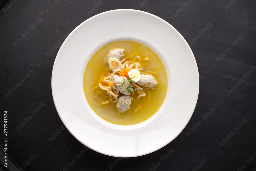 bowl of noodle soup with chicken meatballs on black background bowl of noodle soup with chicken meatballs on black background