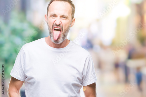 Middle age hoary senior man wearing white t-shirt over isolated background sticking tongue out happy with funny expression. Emotion concept. © Krakenimages.com