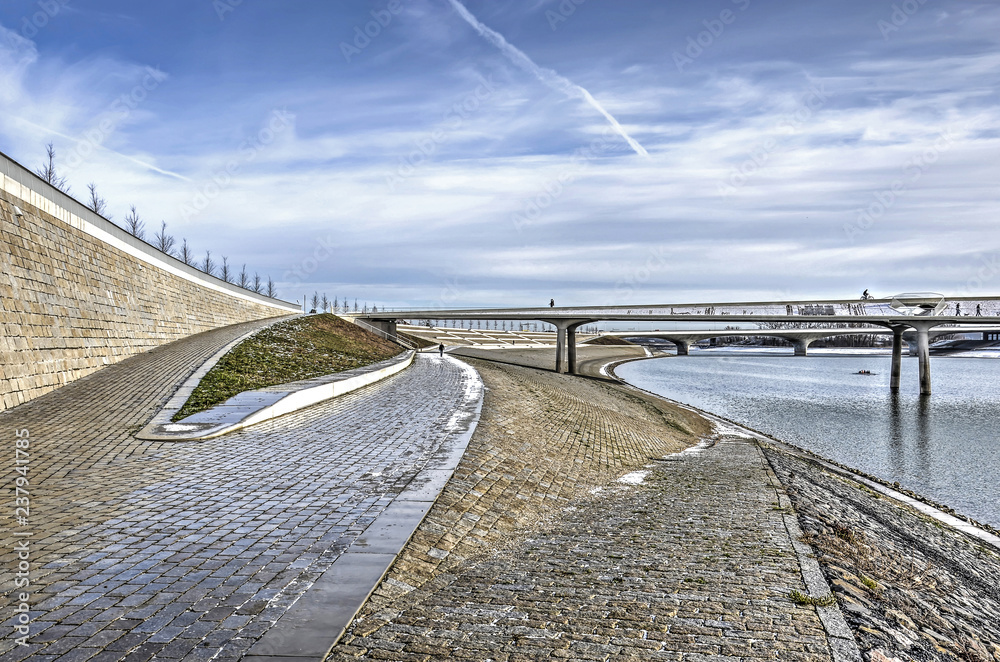 A fascinating composition of slopes, ramps, stairs and walls as well as two bridges at the bank of the new channel of the river Waal near Nijmegen, The Netherlands, on a sunny day in winter A fascinating composition of slopes, ramps, stairs and walls as well as two bridges at the bank of the new channel of the river Waal near Nijmegen, The Netherlands, on a sunny day in winter