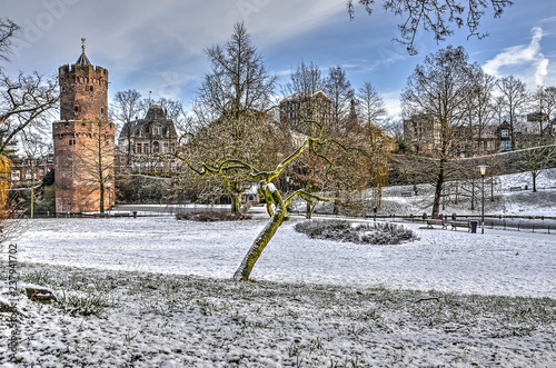 Kronenburg Park in downtwon Nijmegen, The Netherlands, with the medieval Gunpowder Tower covered with a thin layer of fresh snow on a cold day in winter photo