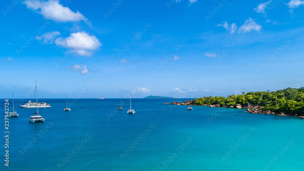 Spectacular aerial view of some yachts and small boats floating on a clear and turquoise sea, Seychelles in the Indian