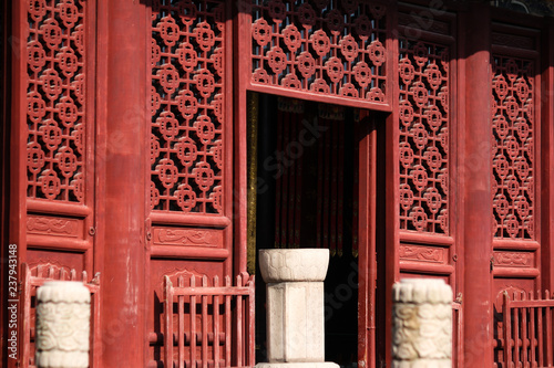 Detailed view onto an entrance area with traditional Chinese red painted wood carving pattern in an old town in China, Asia