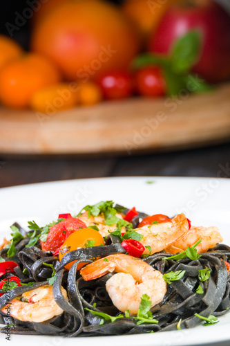 Black squid ink Fettuccine pasta with prawns or shrimps cherry tomatoes, parsley, chili in wine and butter sauce.