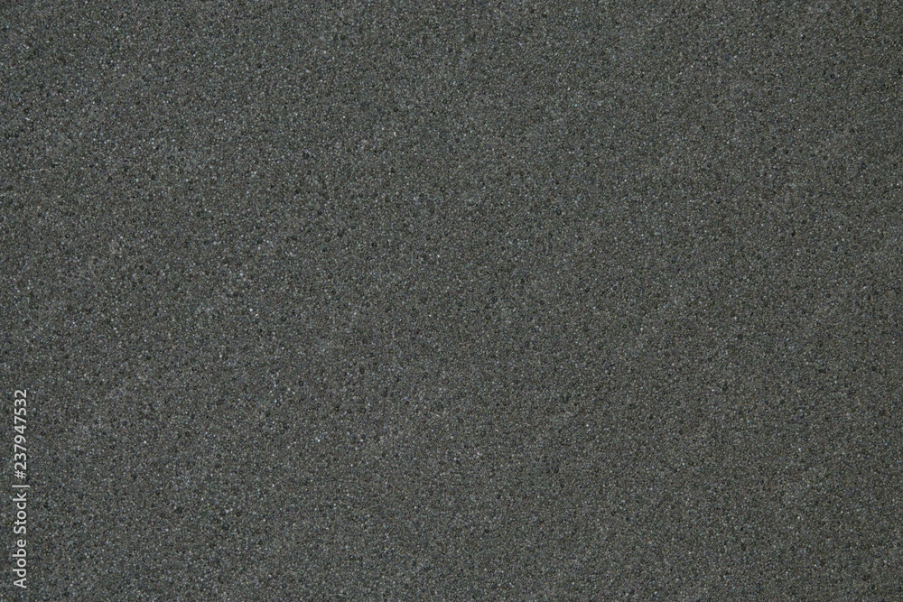 The detail of small bubbles in a solid piece of black foam is shown in a macro view. The detail of small bubbles in a solid piece of black foam is shown in a macro view.