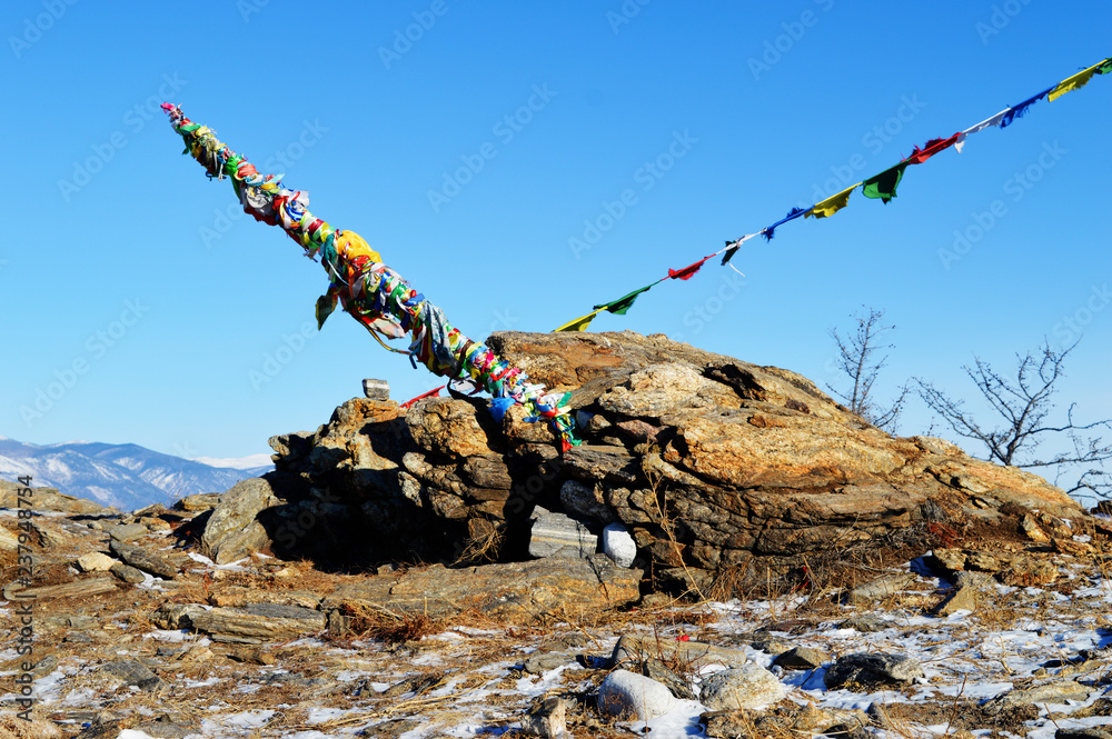 Obraz premium Buddhist multicolored bright ribbons in winter in sunny day at Ogoy Island, Baikal Lake , Russia