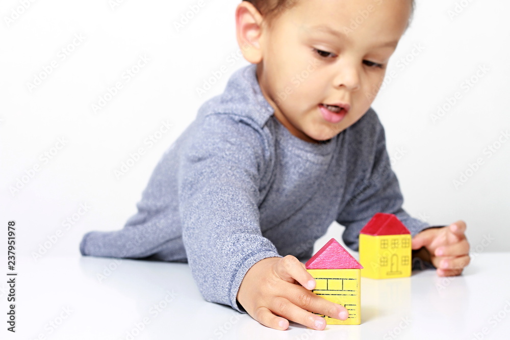 Little boy playing with miniature toy block houses representing property purchase Little boy playing with miniature toy block houses representing property purchase