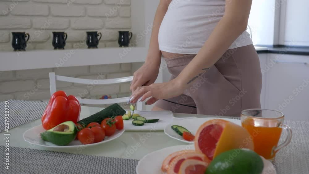 natural food for pregnancy, maternity girl with big abdomen is cooking useful salad for healthy tasty lunch from fresh vegetables at cuisine natural food for pregnancy, maternity girl with big abdomen is cooking useful salad for healthy tasty lunch from fresh vegetables at cuisine
