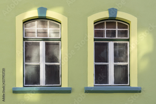 Two windows on a green wall