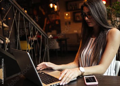 Young pretty caucasian woman in cafe in city centre with tablet laptop