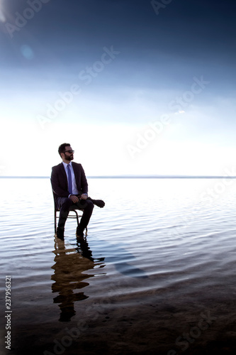 A business man in a suit with an umbrella on top of a lake. amazing surreal business world