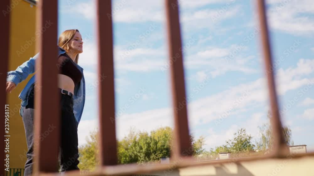 A young woman dancing outside behind the fence. Medium shot A young woman dancing outside behind the fence. Medium shot