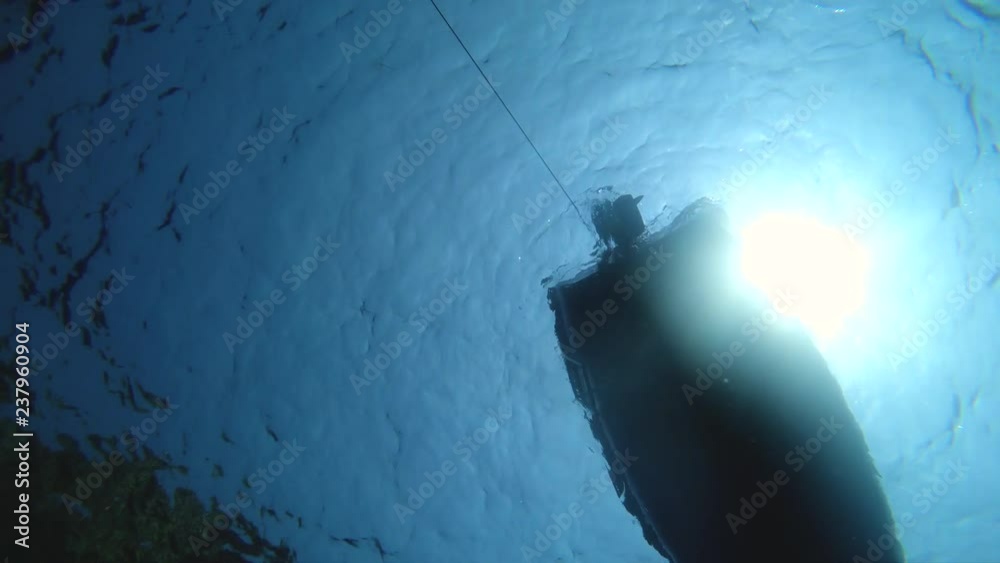 Underwater shot of bottom of boat floating with engine turned down.
