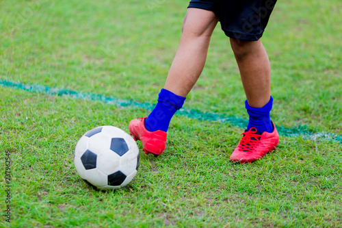 Boy soccer player speed run to shoot ball to goal on green grass. © Koonsiri