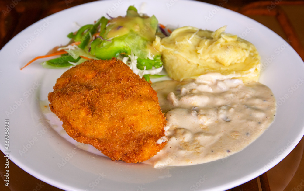 Schnitzel with mashed potato on white plate. Fried chicken cutlet top view photo on wooden table. Tasty lunch served Schnitzel with mashed potato on white plate. Fried chicken cutlet top view photo on wooden table. Tasty lunch served