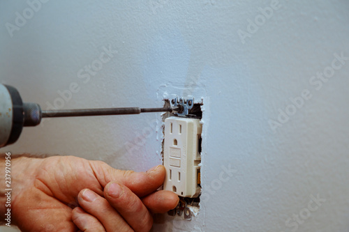 Bild auf Leinwand Tightening a Screw on an Electrical Outlet