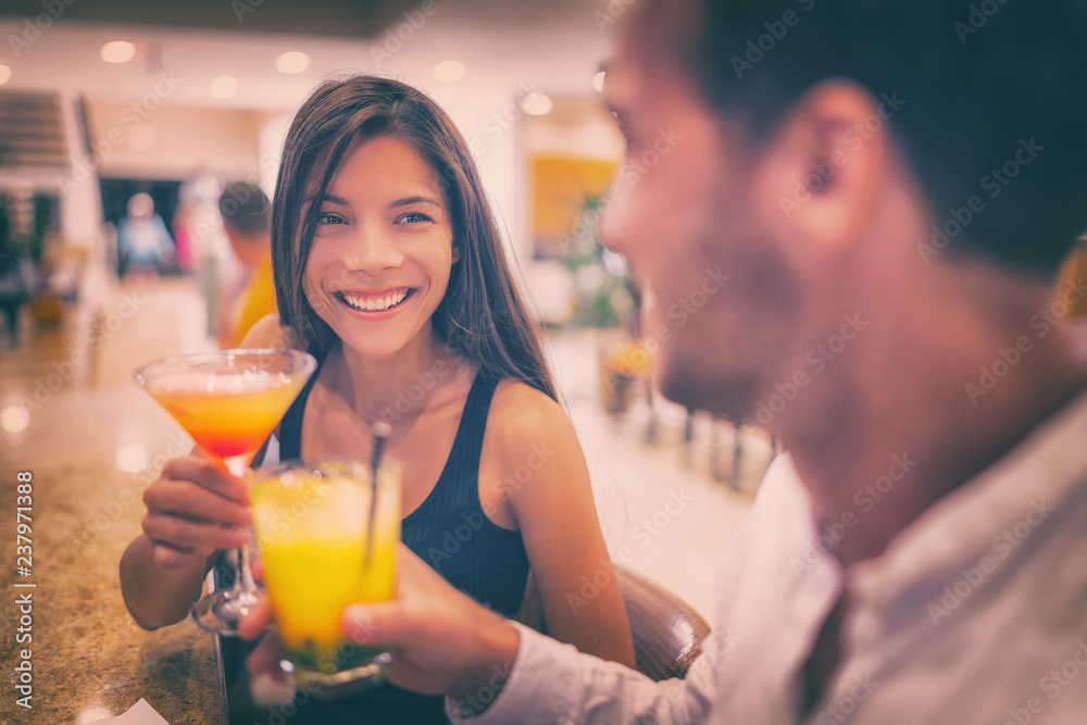 Bar drinking cocktails young couple in love dating talking with drinks at restaurant at night. People at restaurant with alcoholic cocktail beverage. Bar drinking cocktails young couple in love dating talking with drinks at restaurant at night. People at restaurant with alcoholic cocktail beverage.