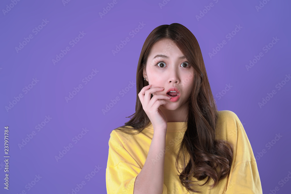 Asian woman shocking for special deals & discounts of promotions, yellow t-shirt clothing, purple background