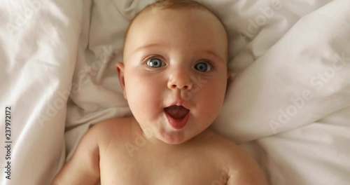 Newborn baby girl laughs lying on her back on the bed
