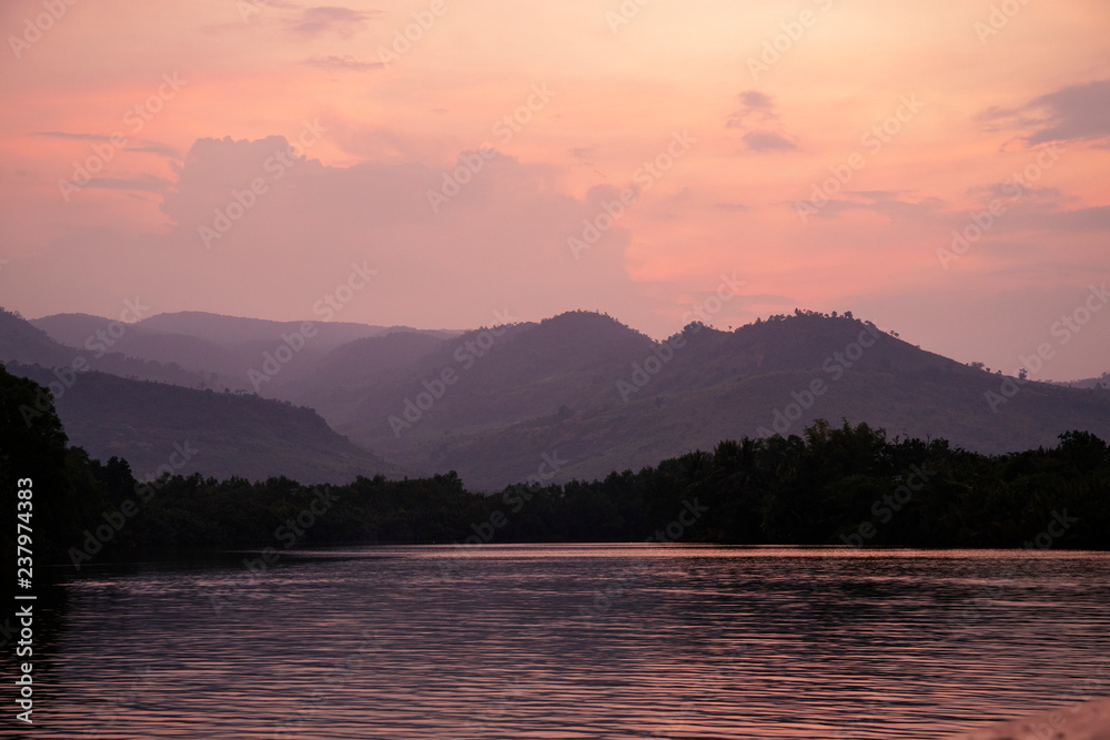 Romantic pink sunset with still lake and distant mountains. Beautiful asian landscape photo. Fresh water river