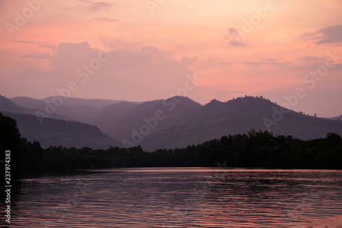 Romantic pink sunset with still lake and distant mountains. Beautiful asian landscape photo. Fresh water river