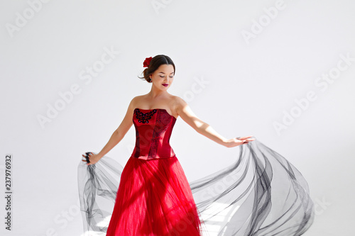 A young woman in a red dress is dancing. Latin style. Isolate on white