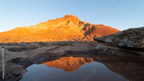 Rainwater in a small pool on top of a sandstone boulder reflects Gooseberry mesa in the last light of a winter day. © Melani