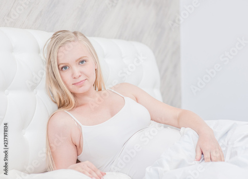 Happy pregnant woman on the bed looking at camera