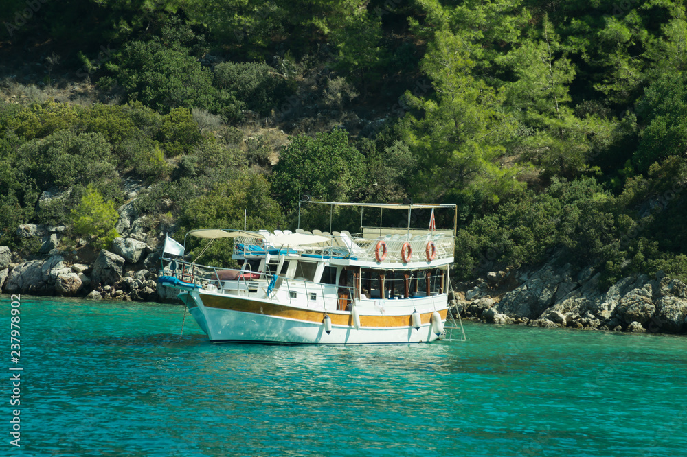 Fototapeta premium Recreation on the boat near the shore of a mountain and forest. beautiful lagoon. ship in the bay. summer vacation