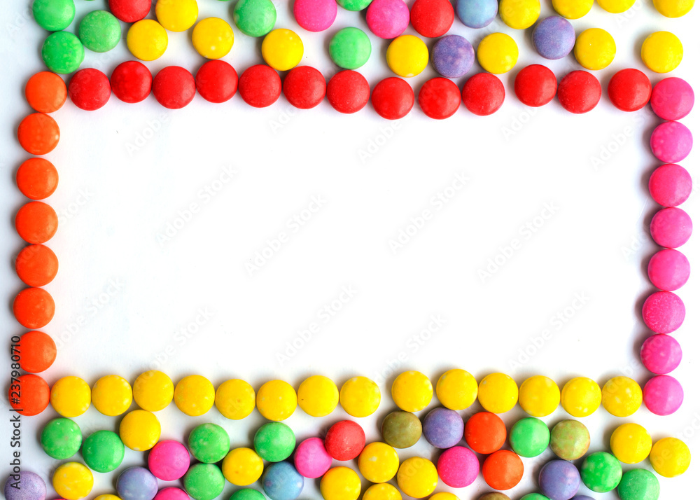 Frame with a pile of colorful chocolate coated candy on white backgrounds Frame with a pile of colorful chocolate coated candy on white backgrounds