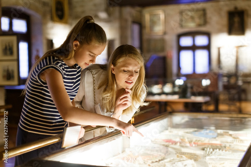 Obraz na płótnie Girl with woman looking with interest at art objects under glass in museum