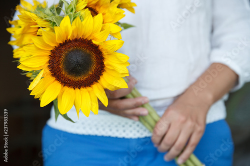 Fototapeta Naklejka Na Ścianę i Meble -  Young woman holding big beautiful sunflowers. Holiday concept