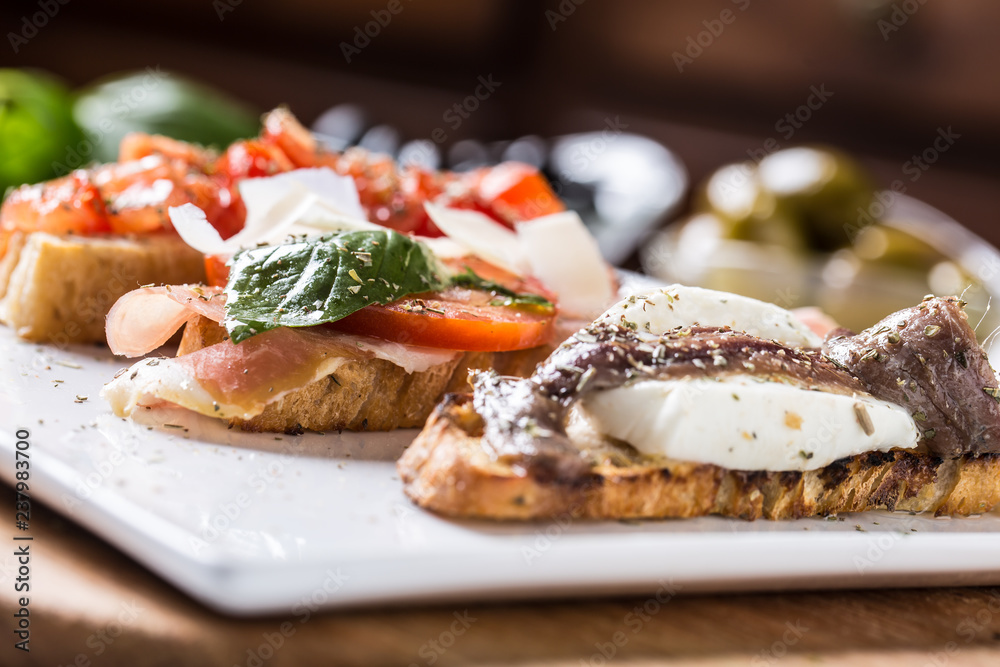 Tasty italian appetizer bruschettes with tomatoes anchovies prosciutto and mozarella Tasty italian appetizer bruschettes with tomatoes anchovies prosciutto and mozarella