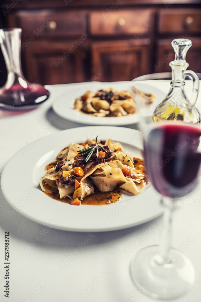 Idalian pasta pappardelle with beef ragout on white plate and red wine Idalian pasta pappardelle with beef ragout on white plate and red wine