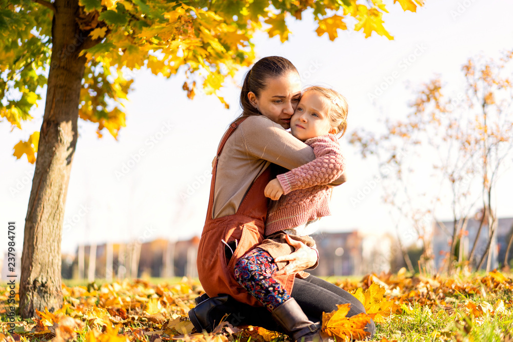 mother and daughter playing in the autumn park