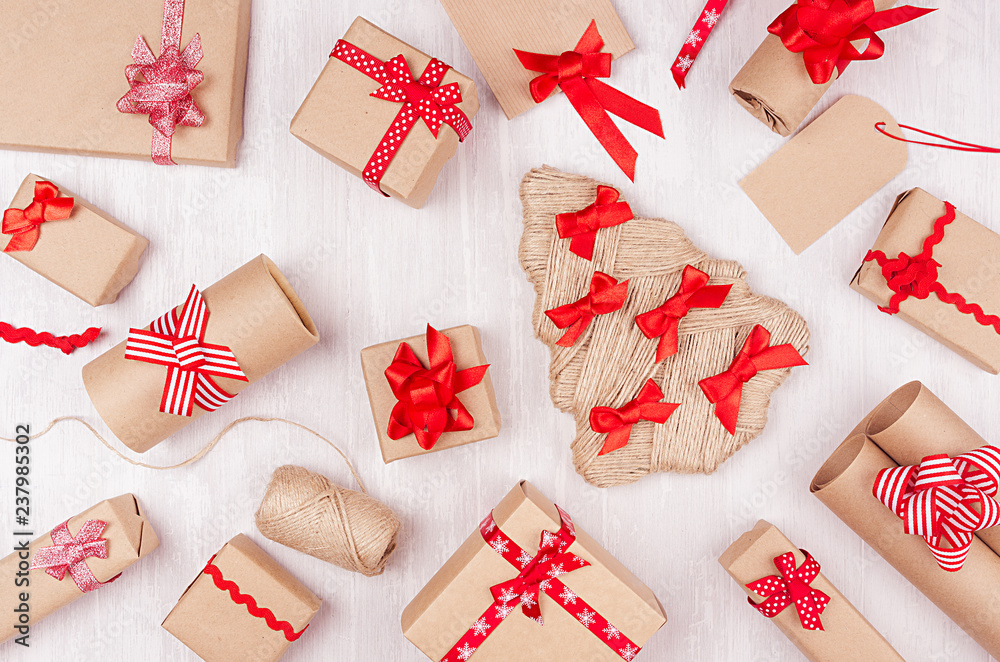 Christmas festive background - different gifts boxes of kraft paper, blank labels and red ribbons, bows on soft white wood board, pattern. Christmas festive background - different gifts boxes of kraft paper, blank labels and red ribbons, bows on soft white wood board, pattern.