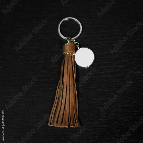 Brown Leather Tassel key ring on black wooden background. Fashion leather key chain for decoration.