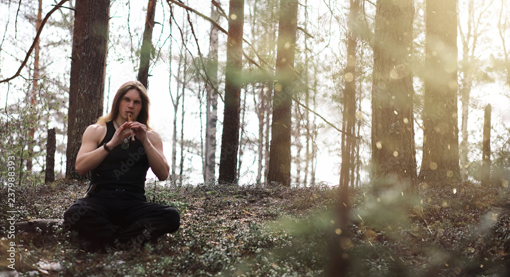 A musician with a tool in nature. A man is playing a flute in a pine forest. The music of the druids in the spring forest. A musician with a tool in nature. A man is playing a flute in a pine forest. The music of the druids in the spring forest.