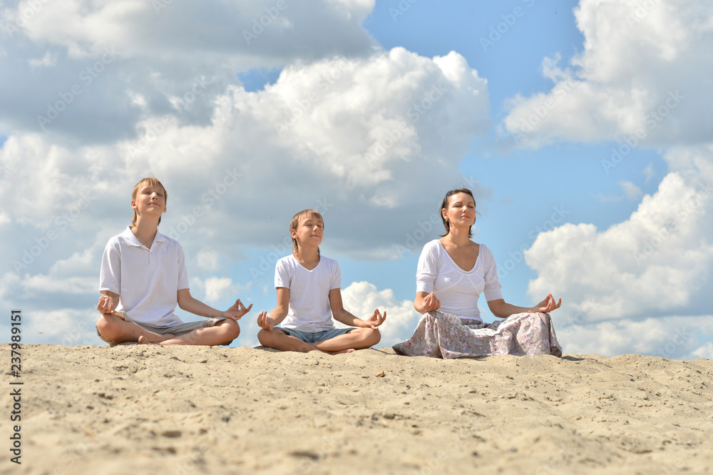 Portrait of happy family on beach practicing yoga Portrait of happy family on beach practicing yoga
