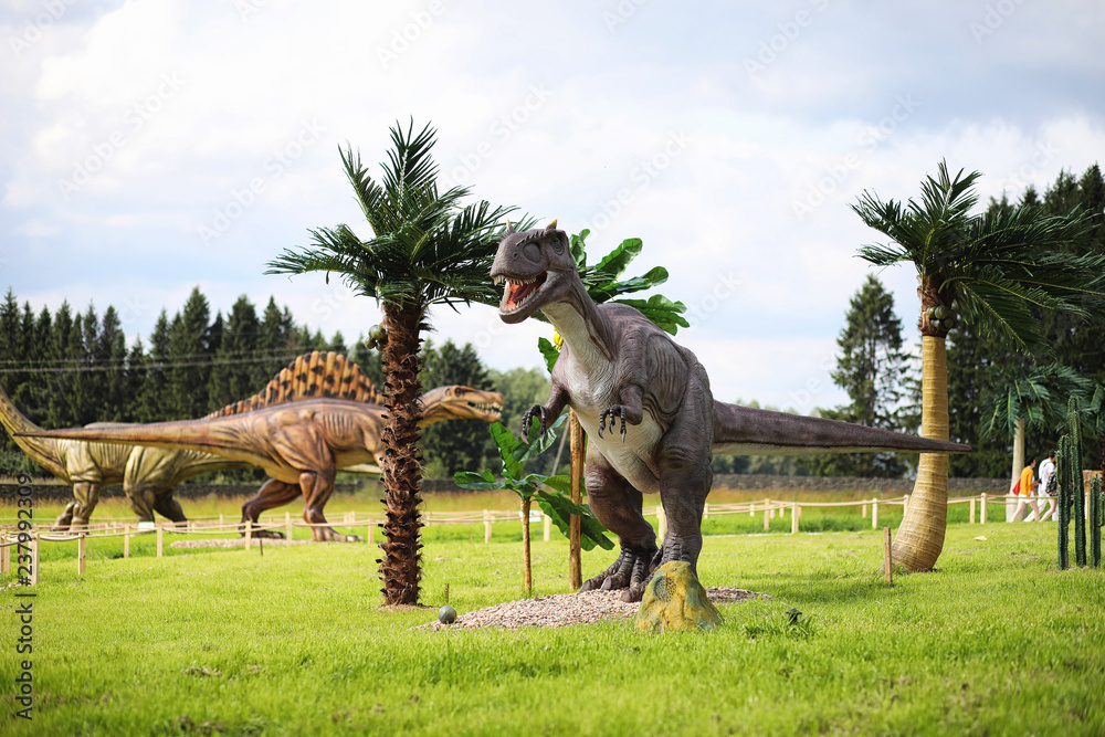Fototapeta premium Park dinozaurów. Dinozaur na tle przyrody. Zabawkowe dinozaury w parku rozrywki.